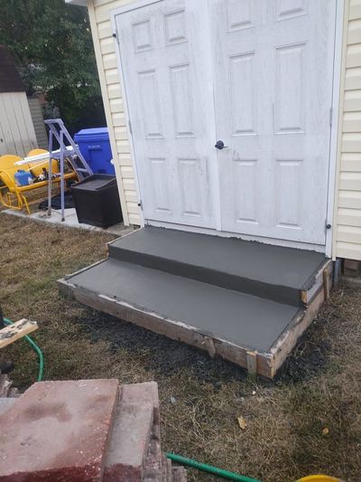 Two new poured concrete steps at a pair of double doors
