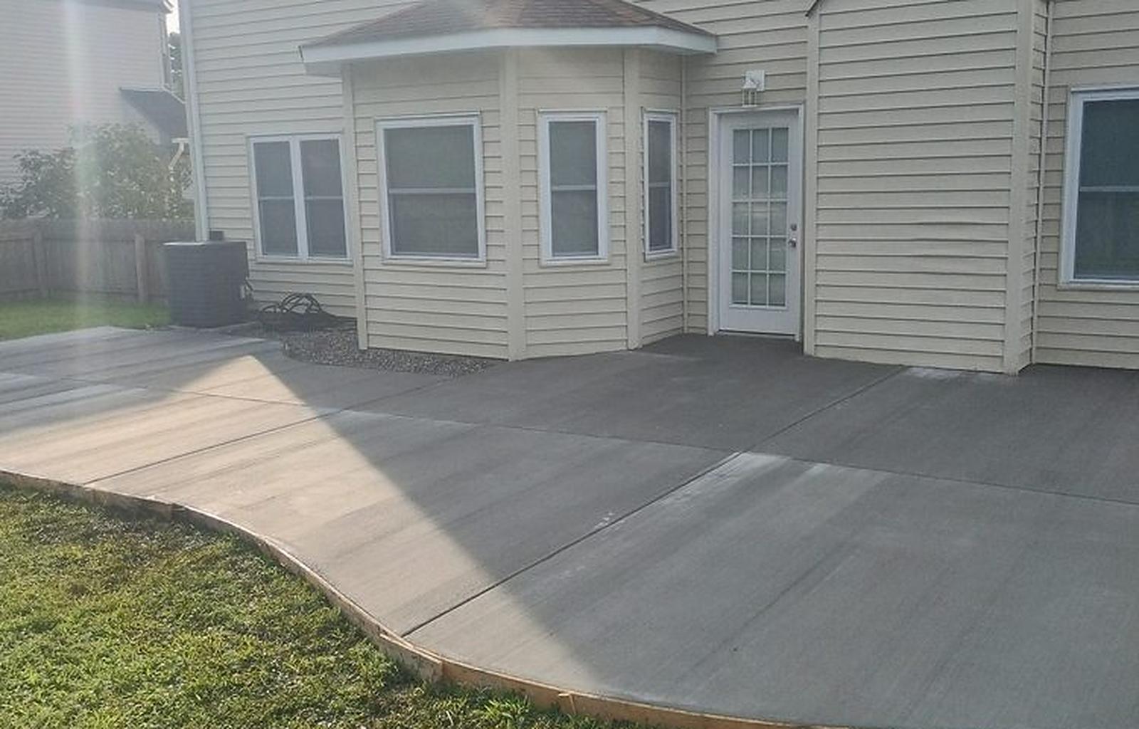 Large poured concrete patio at the rear of a two story house